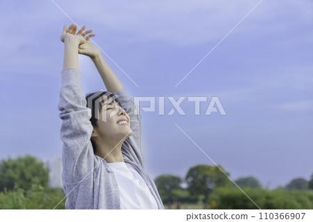Young woman looking up at the blue sky on the bank 110366907