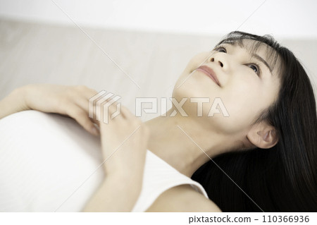 A young woman in a tank top lying down and relaxing 110366936
