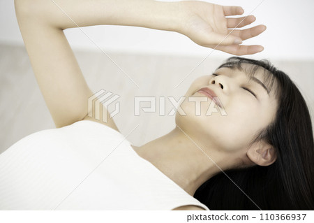 A young woman in a tank top lying down and relaxing 110366937