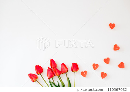 Valentine's Day frame made of a bouquet of red tulips, hearts on a white background with a copy space 110367082