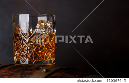 Whiskey glass with ice on a rustic barrel, a classic sip Whiskey glass with ice on a rustic barrel, a classic sip 110367645