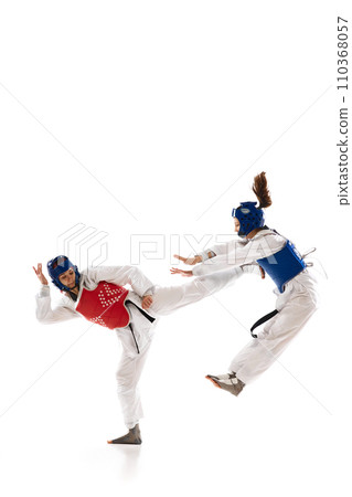 Full-length dynamic image of young girls in white dobok practicing, raining taekwondo isolated over white background 110368057