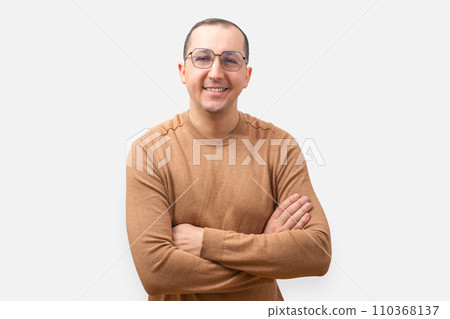 Young man in a casual sweater and glasses on a light background. Positive man with crossed arms looking at camera Young man in a casual sweater and glasses on a light background. Positive man with crossed arms looking at camera 110368137