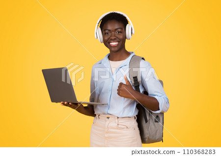 Cheerful young african american woman student in wireless headphones, listen music Cheerful young african american woman student in wireless headphones, listen music 110368283