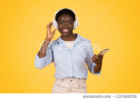Cheerful millennial african american lady student in wireless headphones, listen music Cheerful millennial african american lady student in wireless headphones, listen music 110368288