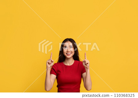 Cheerful asian woman pointing at copy space above her head Cheerful asian woman pointing at copy space above her head 110368325