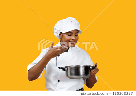 Satisfied black female chef smelling the flavor from a cooking pot 110368357