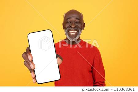Cheerful senior Black man presenting a smartphone with a blank screen, smiling broadly 110368361