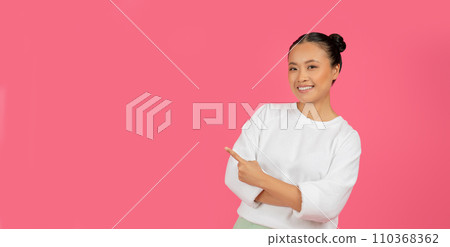 Energetic Asian woman gesturing to the right at empty space 110368362