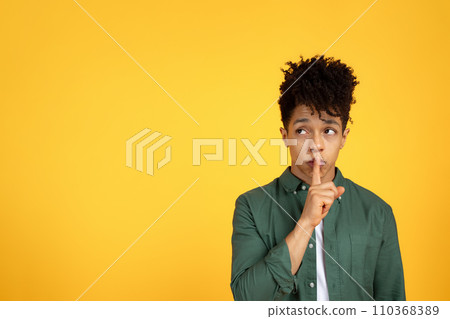 Quiet guy showing silence gesture and looking at copy space 110368389