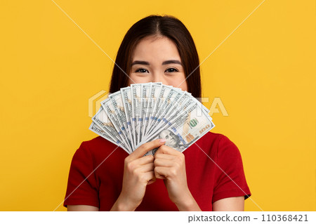 Happy asian woman holding bunch of money over her face Happy asian woman holding bunch of money over her face 110368421
