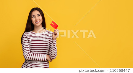 Positive young asian lady showing bank credit card Positive young asian lady showing bank credit card 110368447
