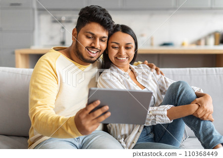 Happy Indian Couple Watching Videos On Digital Tablet While Relaxing At Home Happy Indian Couple Watching Videos On Digital Tablet While Relaxing At Home 110368449