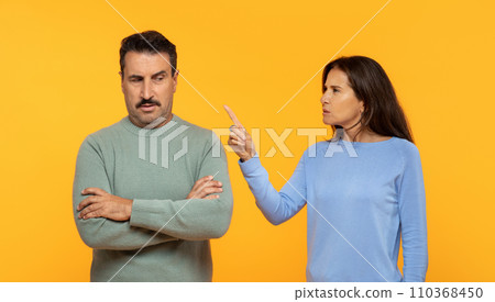 Angry european senior woman appears to be scolding a man who listens with a skeptical expression Angry european senior woman appears to be scolding a man who listens with a skeptical expression 110368450
