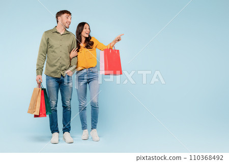 Couple with shopping bags pointing to the side, excited discovery Couple with shopping bags pointing to the side, excited discovery 110368492