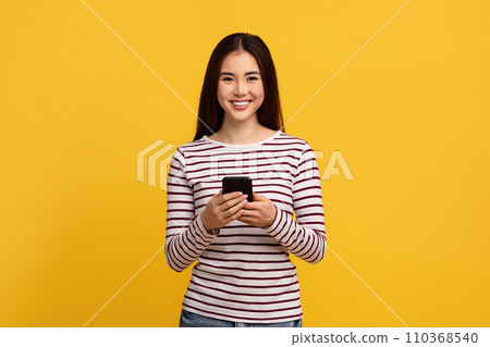 Cute young asian woman holding cell phone Cute young asian woman holding cell phone 110368540