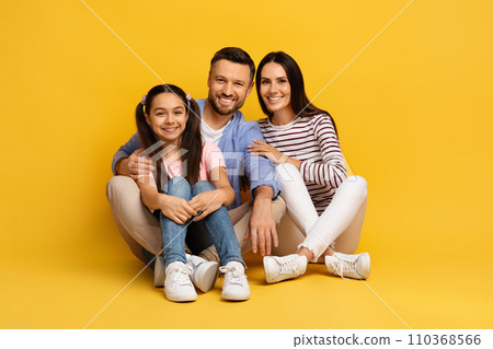 Happy european family of three sitting on floor and embracing 110368566