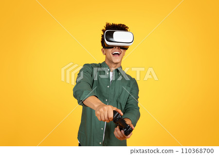 Young black guy wearing VR headset enjoying playing video games 110368700