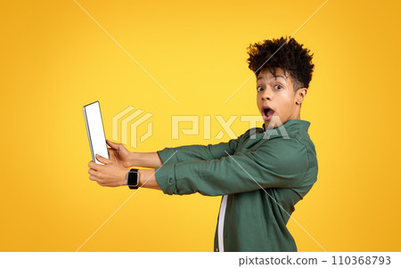 Amazed young black guy holding digital tablet with blank screen Amazed young black guy holding digital tablet with blank screen 110368793