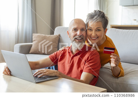 Online banking. Senior couple with laptop and credit card at home Online banking. Senior couple with laptop and credit card at home 110368986