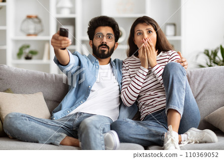 Shocked millennial indian couple watching TV together at home 110369052