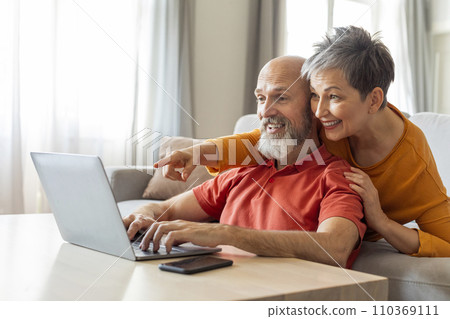 Digital Entertainment. Cheerful Elderly Couple Using Laptop At Home Together Digital Entertainment. Cheerful Elderly Couple Using Laptop At Home Together 110369111