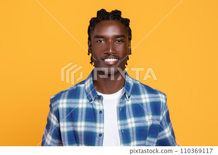 Confident young black man with braided hair posing on yellow background 110369117