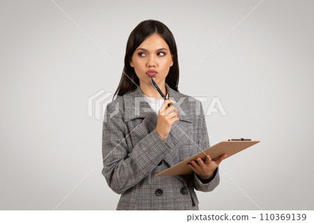 Pensive businesswoman with clipboard, contemplating ideas Pensive businesswoman with clipboard, contemplating ideas 110369139