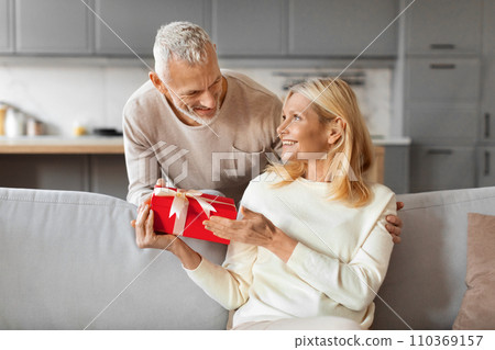 Grey-haired man husband greeting his beautiful wife with Valentine Day Grey-haired man husband greeting his beautiful wife with Valentine Day 110369157