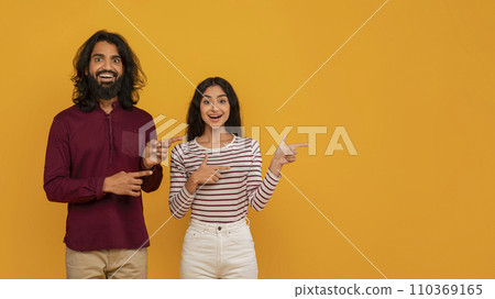 Amazed young indian couple pointing up at copy space Amazed young indian couple pointing up at copy space 110369165