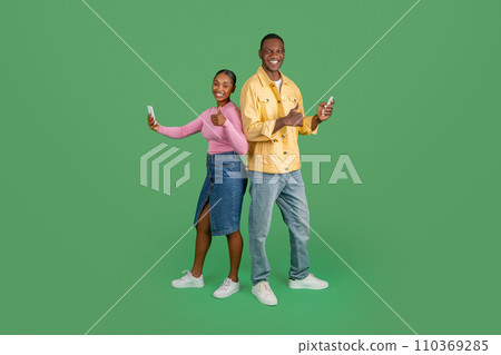 Happy black man and woman with phones in their hands Happy black man and woman with phones in their hands 110369285