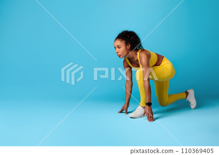 Black Lady Runner Standing In Crouch Start Position, Blue Background Black Lady Runner Standing In Crouch Start Position, Blue Background 110369405