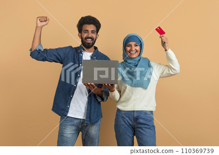 Happy young muslim couple with laptop and credit card celebrating success Happy young muslim couple with laptop and credit card celebrating success 110369739