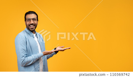 A smiling man with a beard and glasses holds his hand flat and extended A smiling man with a beard and glasses holds his hand flat and extended 110369742