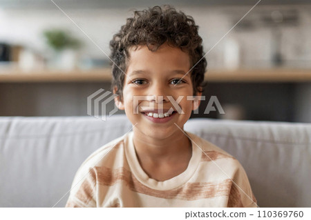 Cheerful black boy with curly hair and bright smile looking at camera 110369760