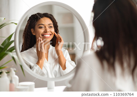 Beautiful black woman at home admiring her reflection in the mirror 110369764