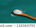 Coarse salt crystals on a blue table. Wooden spoon 110369795