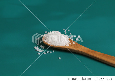 Coarse salt crystals on a blue table. Wooden spoon Coarse salt crystals on a blue table. Wooden spoon 110369795
