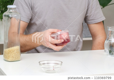 A man lays an egg and shakes a container of rice A man lays an egg and shakes a container of rice 110369799