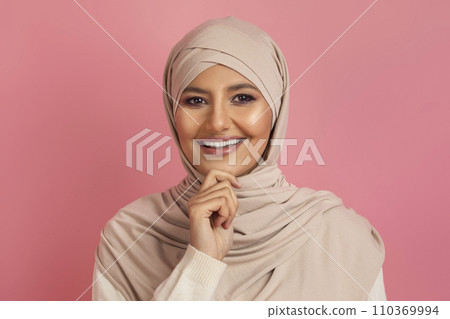 Smiling muslim woman in hijab looking at camera and touching chin 110369994