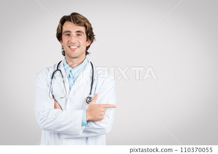 Smiling doctor pointing to the side, stethoscope visible 110370055