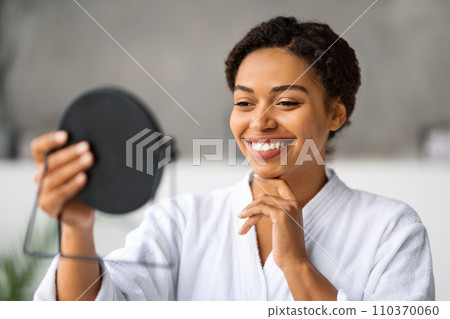 Self-Care Concept. Beautiful Black Woman Holding Handheld Mirror And Touching Face Self-Care Concept. Beautiful Black Woman Holding Handheld Mirror And Touching Face 110370060