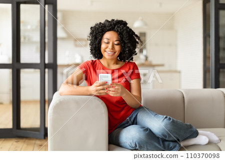 Mobile Communication. Beautiful young black female using smartphone at home Mobile Communication. Beautiful young black female using smartphone at home 110370098