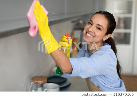 Joyful caucasian woman wiping glass with cloth and spray 110370166