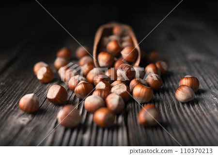 Hazelnut nuts pour out of wooden scoop 110370213