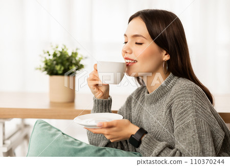 Closeup of happy young woman drinking coffee at home Closeup of happy young woman drinking coffee at home 110370244