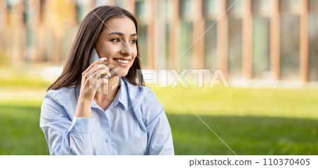 Cheerful young professional woman having a pleasant conversation on her phone 110370405