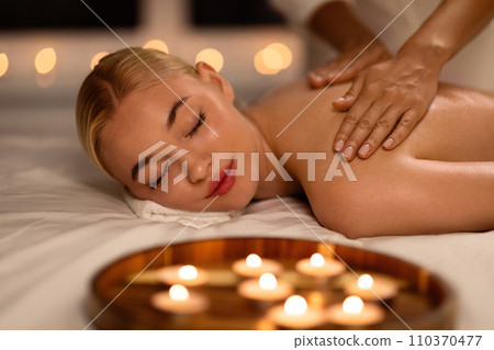 Blonde Lady Enjoying Back and Shoulders Massage In Beauty Salon 110370477