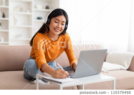 Positive millennial asian woman working or studying from home Positive millennial asian woman working or studying from home 110370498