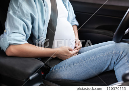 Cropped pregnant lady sitting in driver's seat with safety belt Cropped pregnant lady sitting in driver's seat with safety belt 110370533